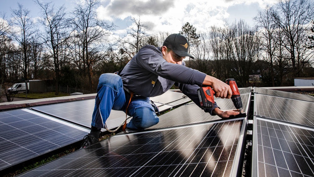 Arbeiter montiert Solarzellen am Dach